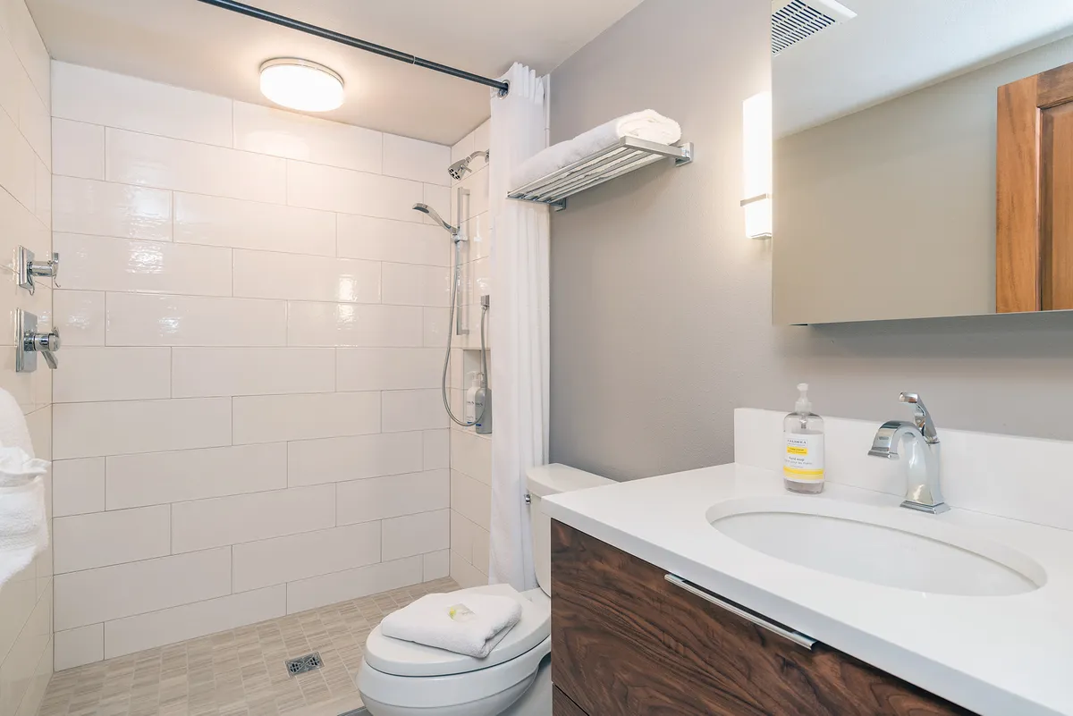 A bright, remodeled bathroom with a sleek vanity, modern fixtures, a walk-in shower, and fresh towels neatly arranged. The clean design and soft lighting create a spa-like, rejuvenating atmosphere, perfect for refreshing after mountain adventures.