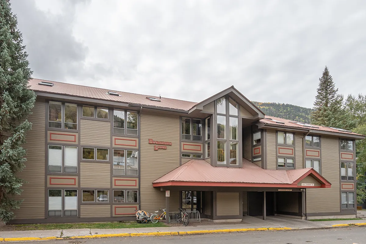A view of the building’s facade with large windows, a welcoming entrance awning, and bicycles parked outside. The sidewalk and approachable entry hint at easy access to both the condo and the broader neighborhood. Mature trees and subtle landscaping surround the property, giving it a sense of place within a walkable community.