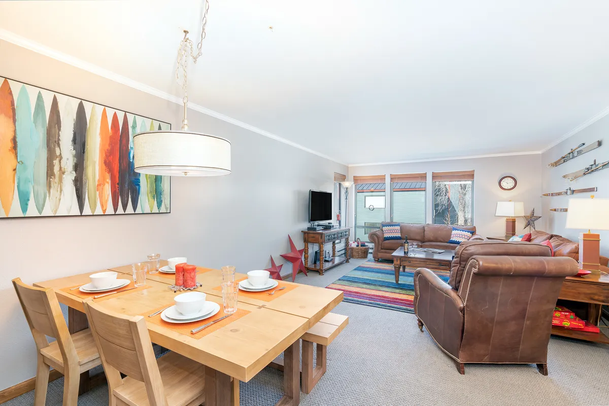 A warm, inviting entryway and dining area with a set table, colorful wall art, and comfortable seating. The space feels cheerful and lived-in, suggesting a welcoming home base to launch your Telluride adventures and return to after exploring.